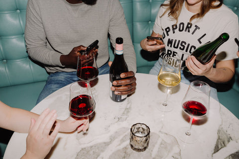 Friends enjoy interesting red and white wine and capture the discovery on their phones