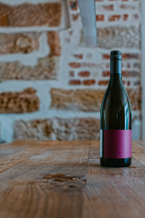 A bottle of red wine to be discovered, on a wooden table in an industrial setting.