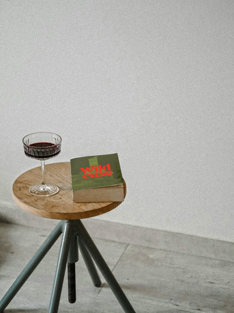 A Wildcase branded book next to a glass of deep coloured red wine, showing how wine is there to be enjoyed and discovered. 
